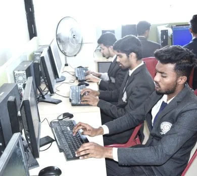 Male students in uniform typing on keyboards and looking at desktop monitors in the computer lab.
