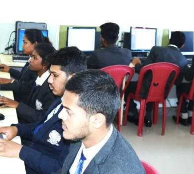 A group of students focused on their desktop screens, using the keyboards in a computer lab setting.