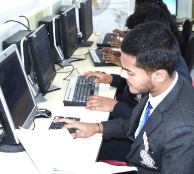 Row of students typing on their keyboards while concentrating on the monitors in the computer laboratory.