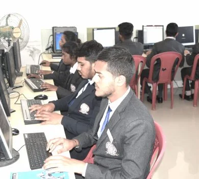 Side view of male students in blazers using desktop computers in the college computer lab.