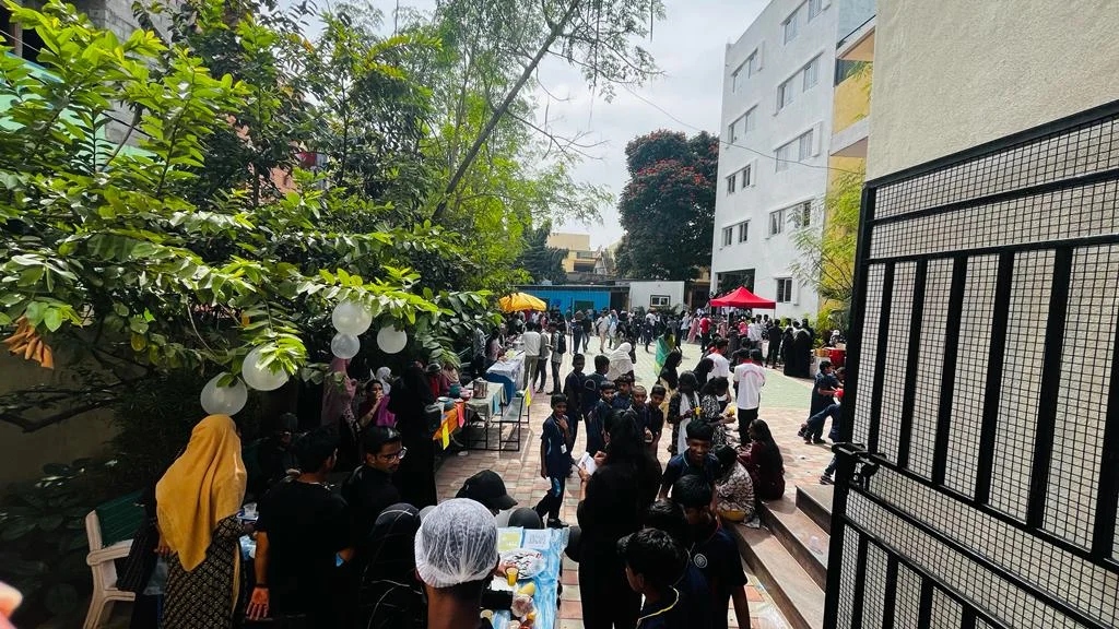 Students and staff gathered in a courtyard with a red canopy, enjoying a food event.