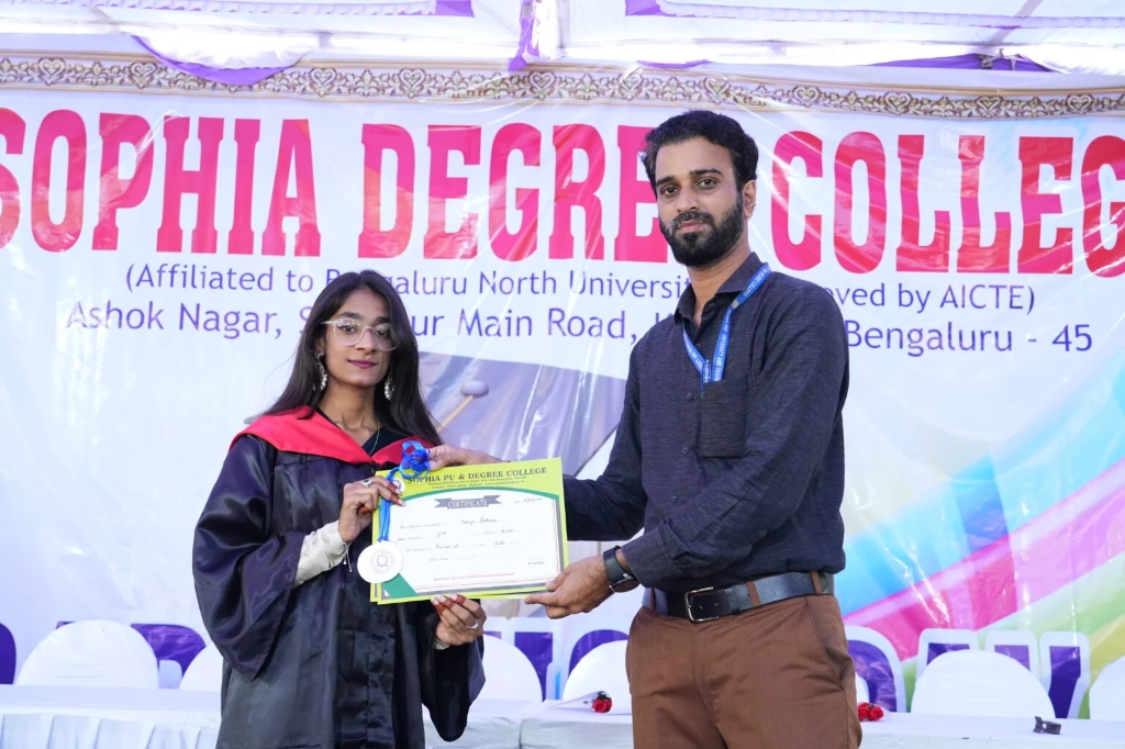 A female graduating student receiving her certificate and medal on stage.