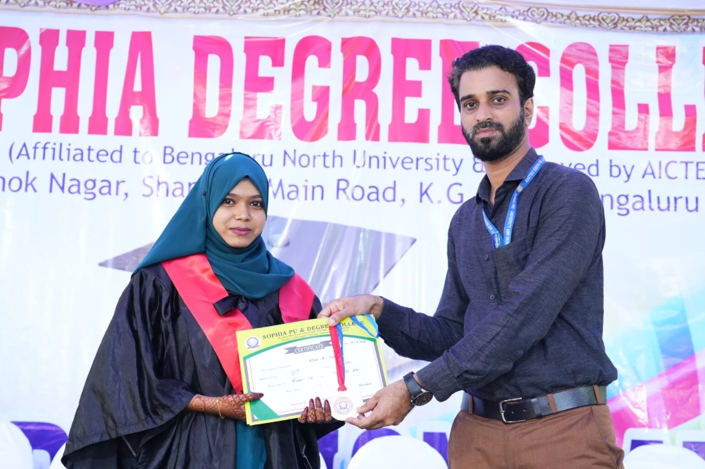 A graduating student receiving a certificate and medal from a staff member.