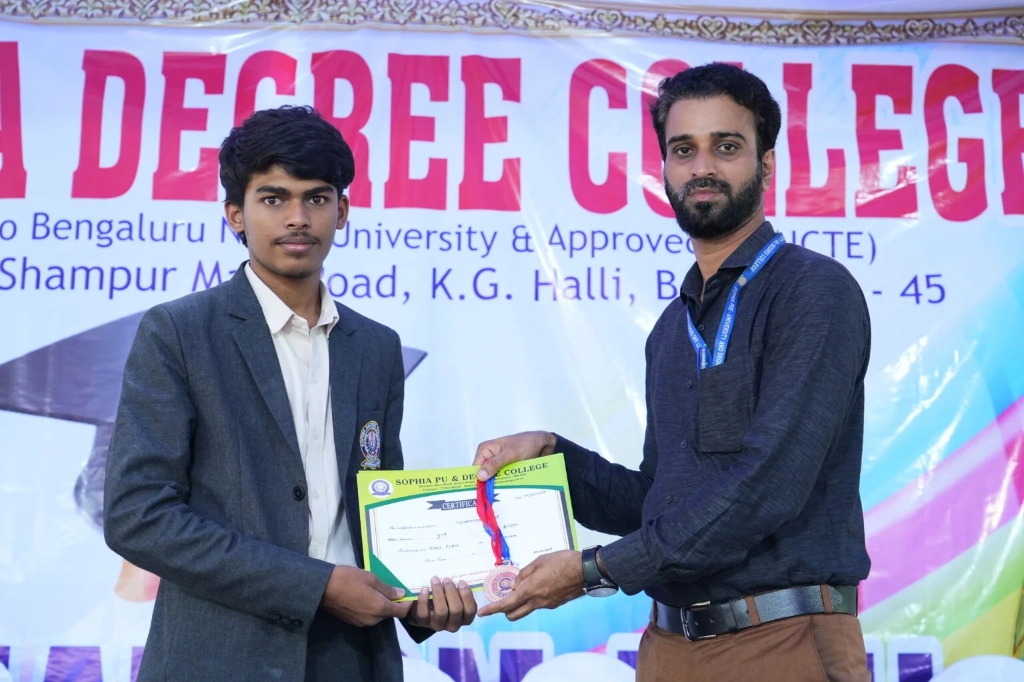 A male student in graduation attire receiving his degree certificate on stage.