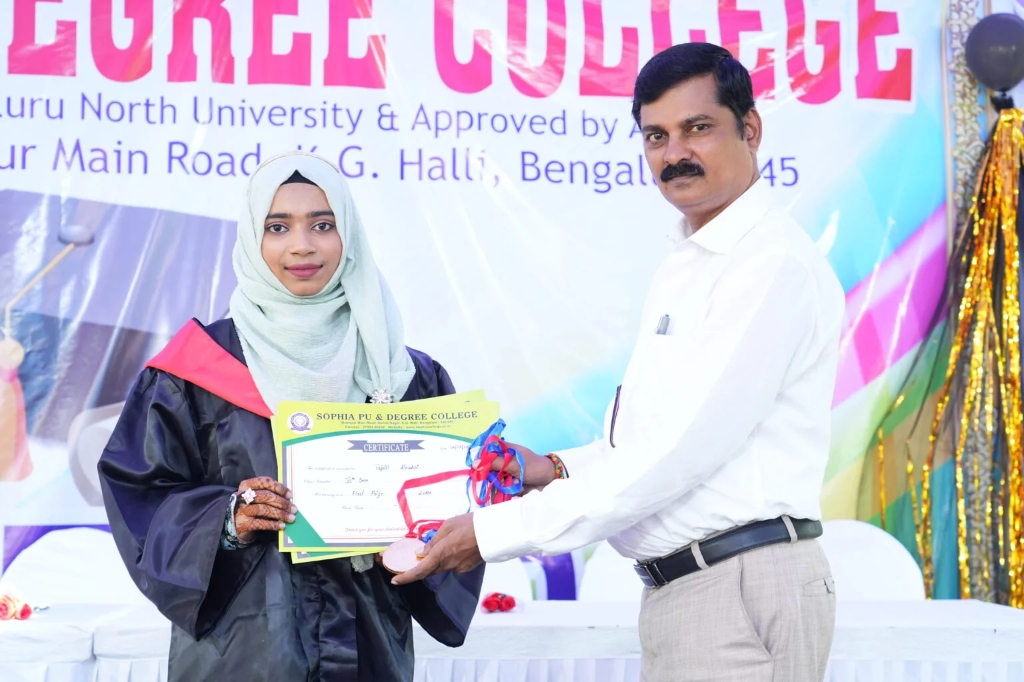 A female graduating student in a hijab receiving her certificate.