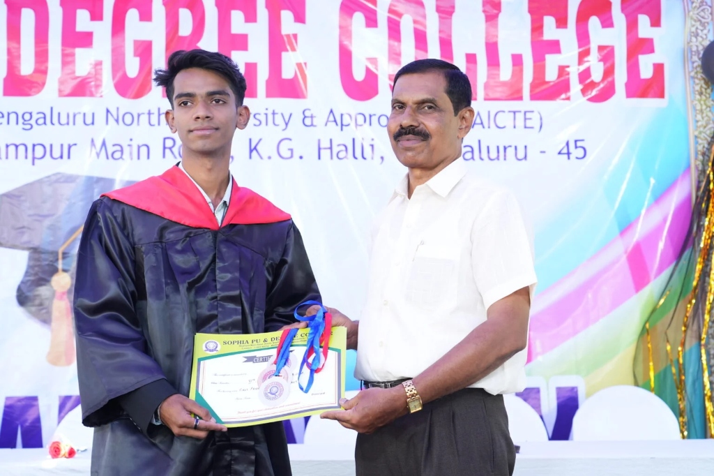 A male graduating student receiving his certificate and medal.