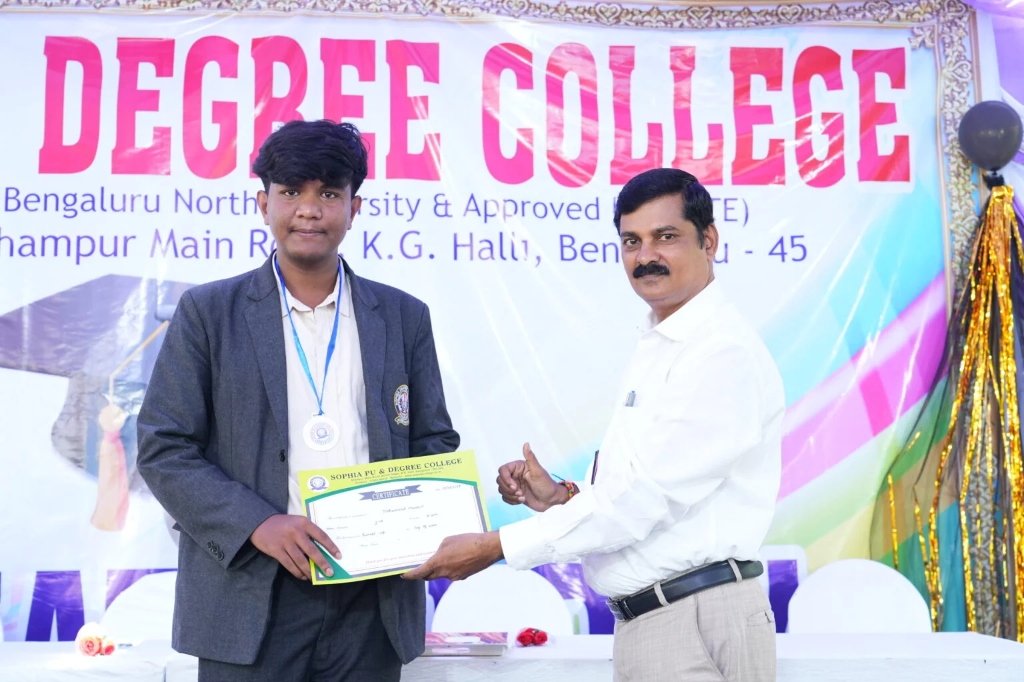 A male student receiving a degree certificate and medal on stage.