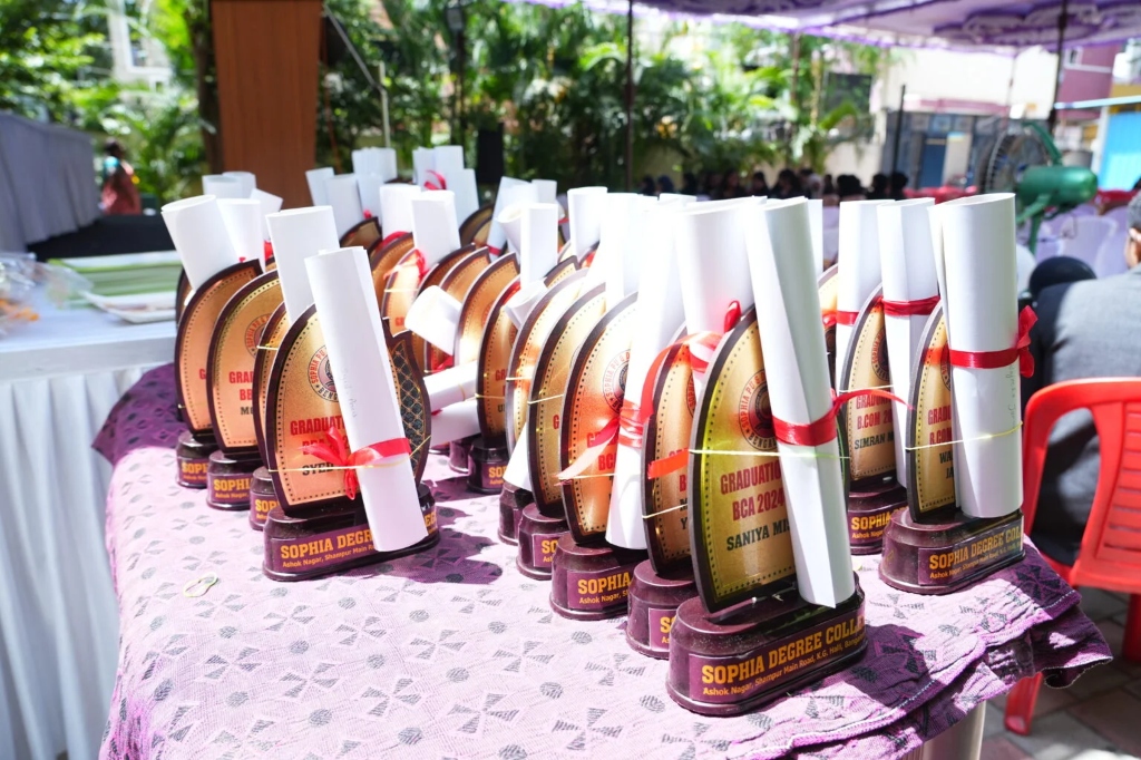 A table full of graduation awards, trophies, and degree scrolls for the graduating students.