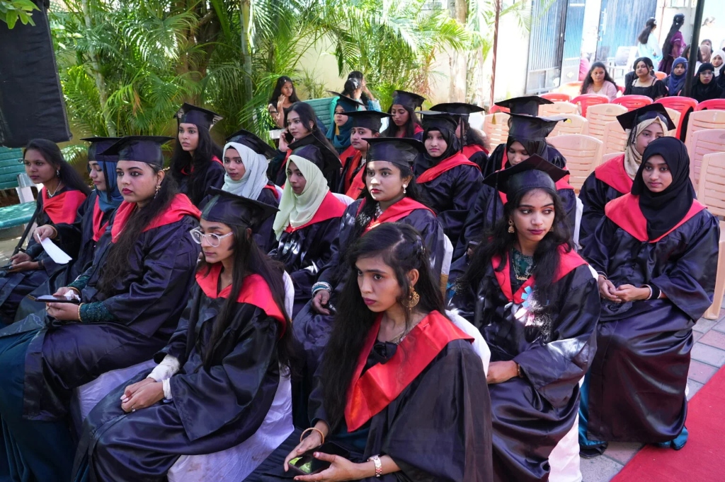 Female graduating students seated in rows wearing graduation gowns and caps.