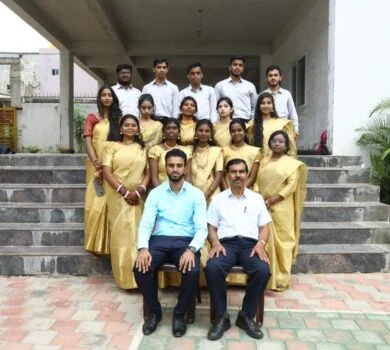 Graduating students in golden sarees and white shirts posing for a group picture.
