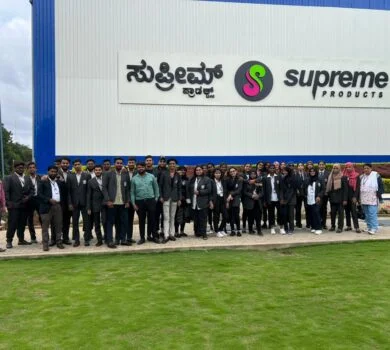 A group of students smiling for a picture outside the Supreme Products factory.