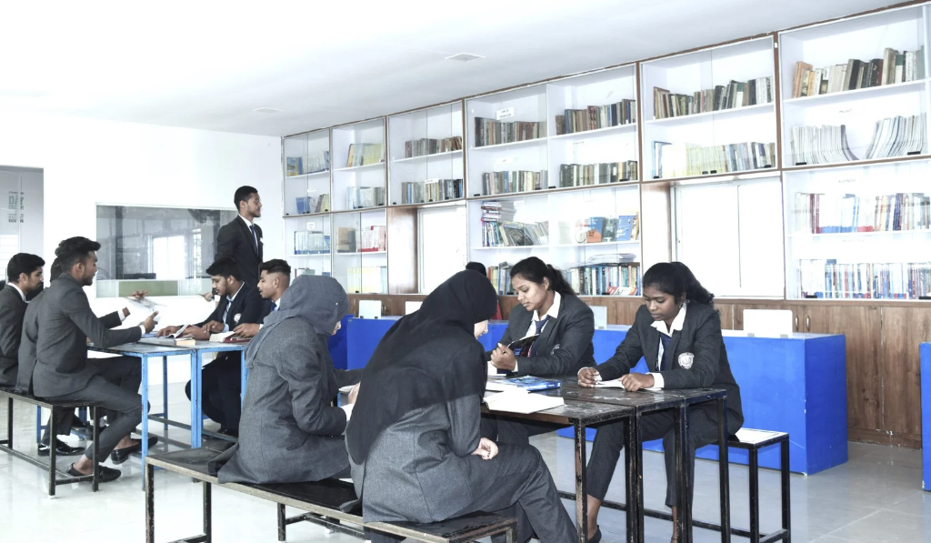 Students studying together at desks in the well-lit library, surrounded by bookshelves.
