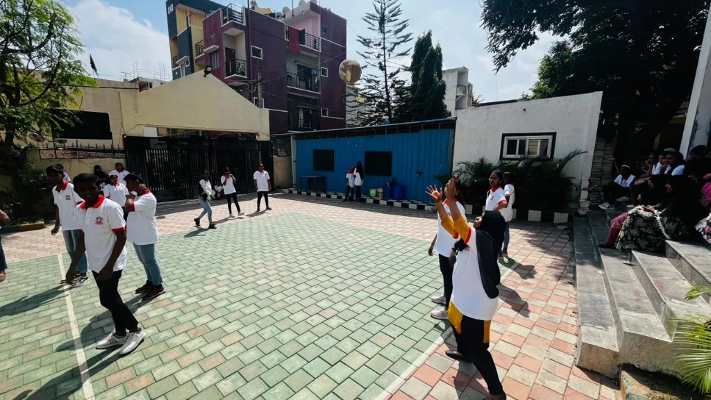 Students playing throwball or volleyball on the outdoor college court.