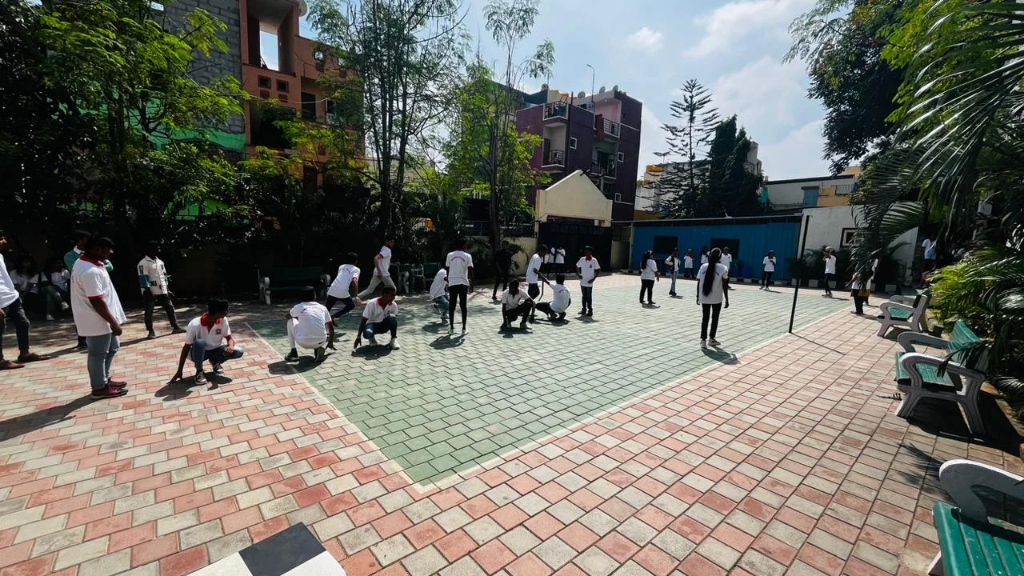 Students sitting by the sidelines while others participate in a sports game.